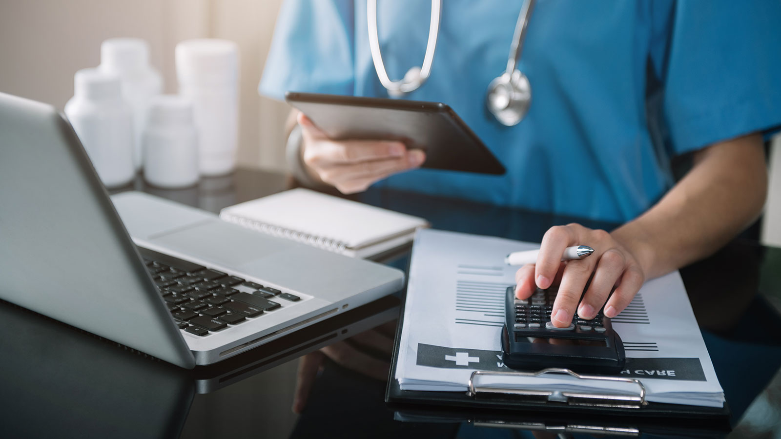 Doctor physician with tablet calculate medical fee costs & revenue. practitioner use calculator at Clinic.