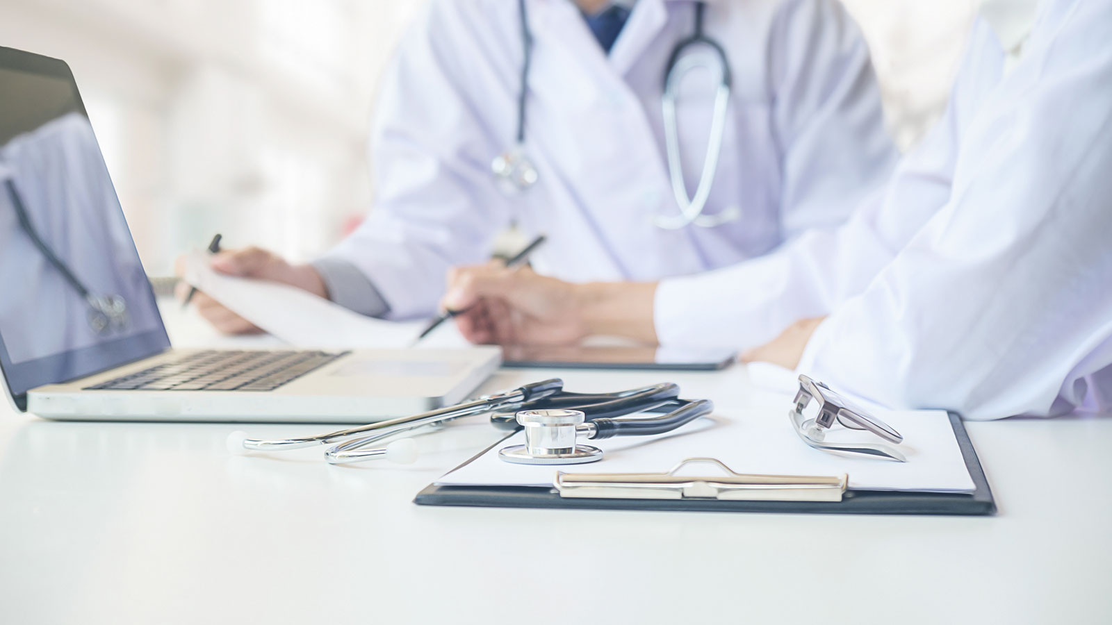 Stethoscope with clipboard and Laptop on desk